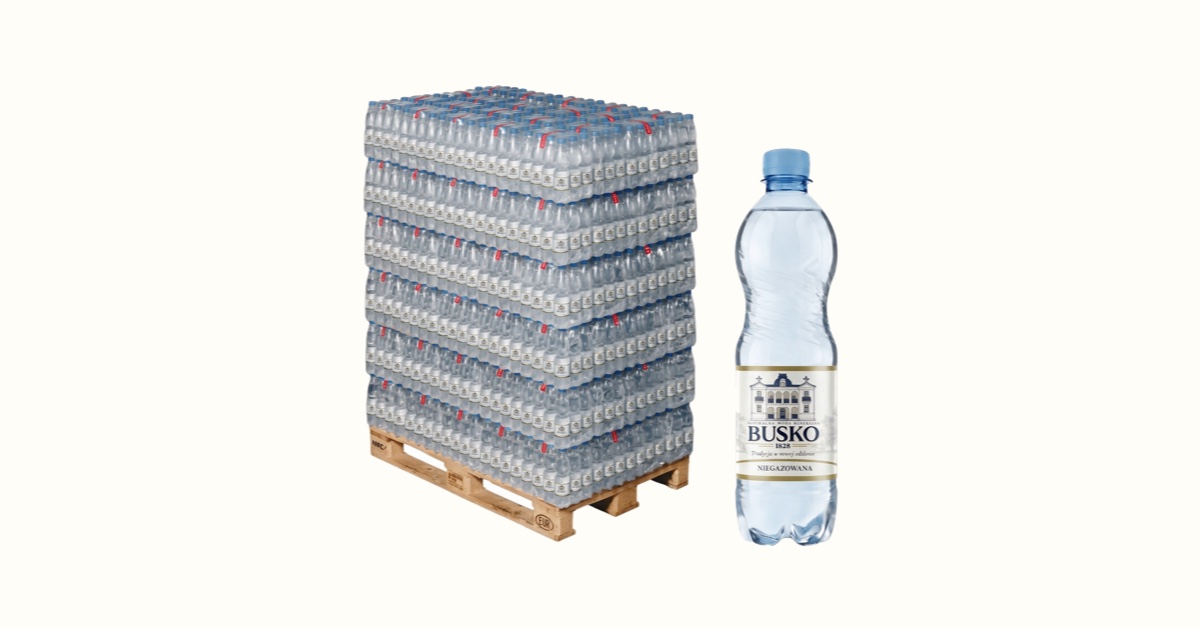 Paleta EUR z zafoliowanymi zgrzewkami wody Busko1828 0,5 l obok pojedynczej butelki niegazowanej.