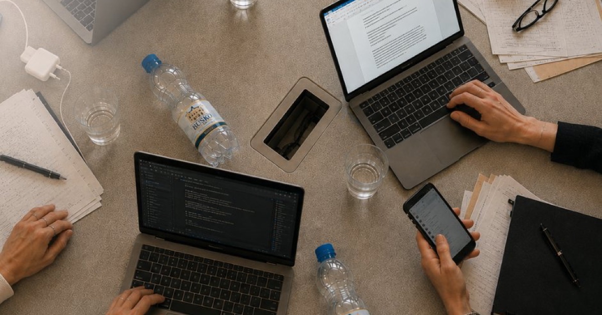 Stół konferencyjny w biurze z laptopami, notatkami i butelkami wody Busko1828.